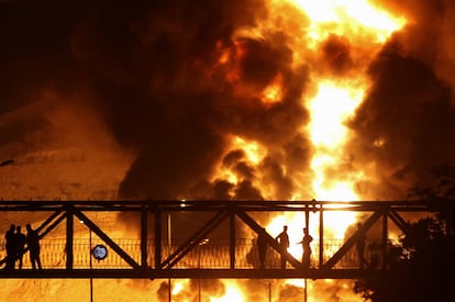 Un grupo de personas observa desde un puente la explosión de una bomba lanzada por Israel sobre la refinería de Shahran, en la capital de Irán.